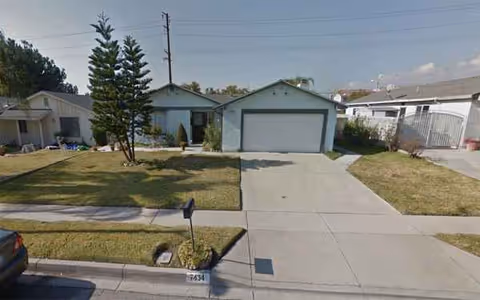 Residential front view featuring a house with a two-car garage, driveway, and lawn.