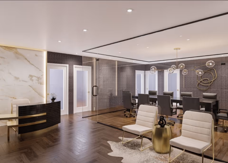 Modern interior space with a reception desk on the left, two white cushioned chairs with gold legs and a small gold side table in the foreground, and a glass-walled conference room with a long table and multiple chairs in the background. The room features wood flooring, marble accent wall, and contemporary lighting fixtures.
