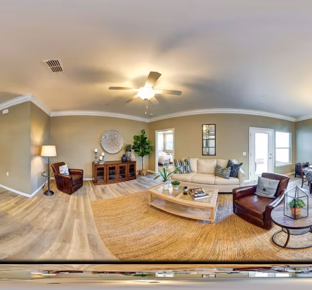 Bright furnished living room with a sofa, two armchairs, coffee table, media console, and ceiling fan.