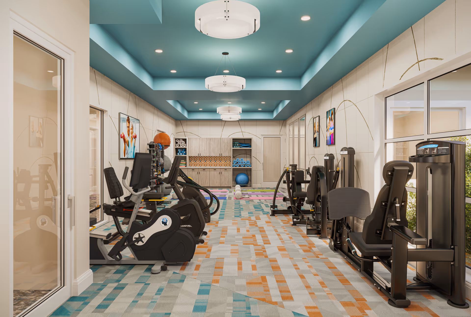 Bright interior fitness room with cardio and strength machines, colorful patterned carpet, teal recessed ceiling, and storage shelves at the far end.