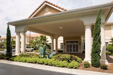 Front entrance of Life Care Center of Pensacola with columns and manicured landscaping.