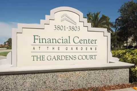 Large white exterior sign with steps and green lettering reading The Gardens Court