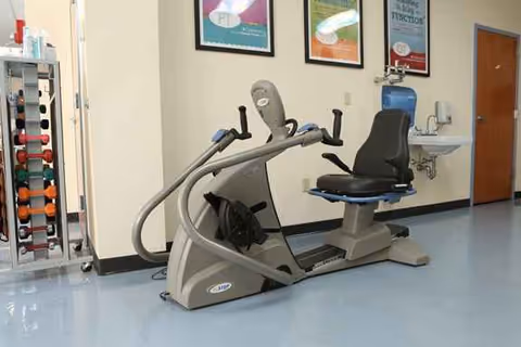 Indoor gym area with a stationary exercise bike, weight rack, and wall posters.