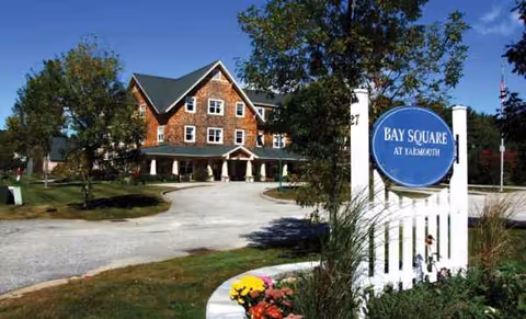 Brick senior living facility exterior with a circular Bay Square at Yarmouth sign.