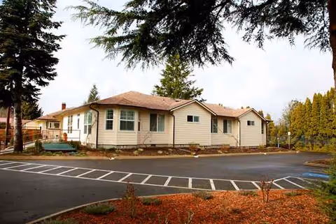 Front exterior of a single-story beige senior living facility with a parking lot.