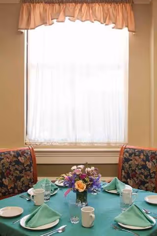 Dining table set for a meal with green napkins and floral centerpiece.
