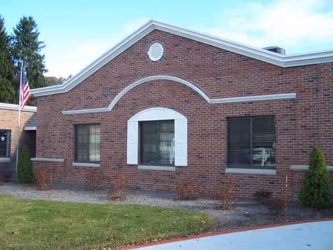 Brick rehabilitation center building with decorative white trim and an American flag outside.