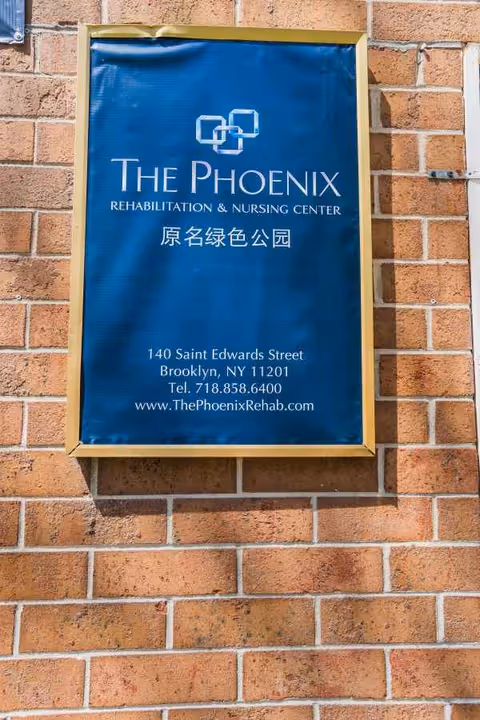 Blue framed sign on a brick wall advertising The Phoenix Rehabilitation & Nursing Center.