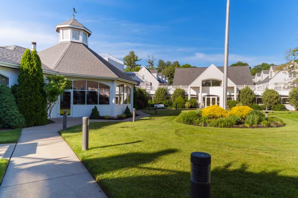 Landscaped courtyard and front entrance of Pomperaug Woods with a round pavilion on the left and the main building beyond.