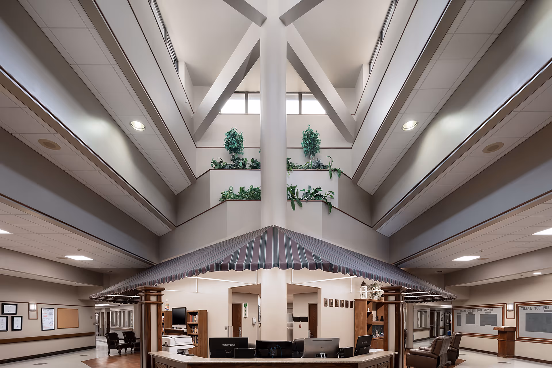 Spacious multi-story atrium and reception area with a central desk under a striped canopy, seating, and balconies above.