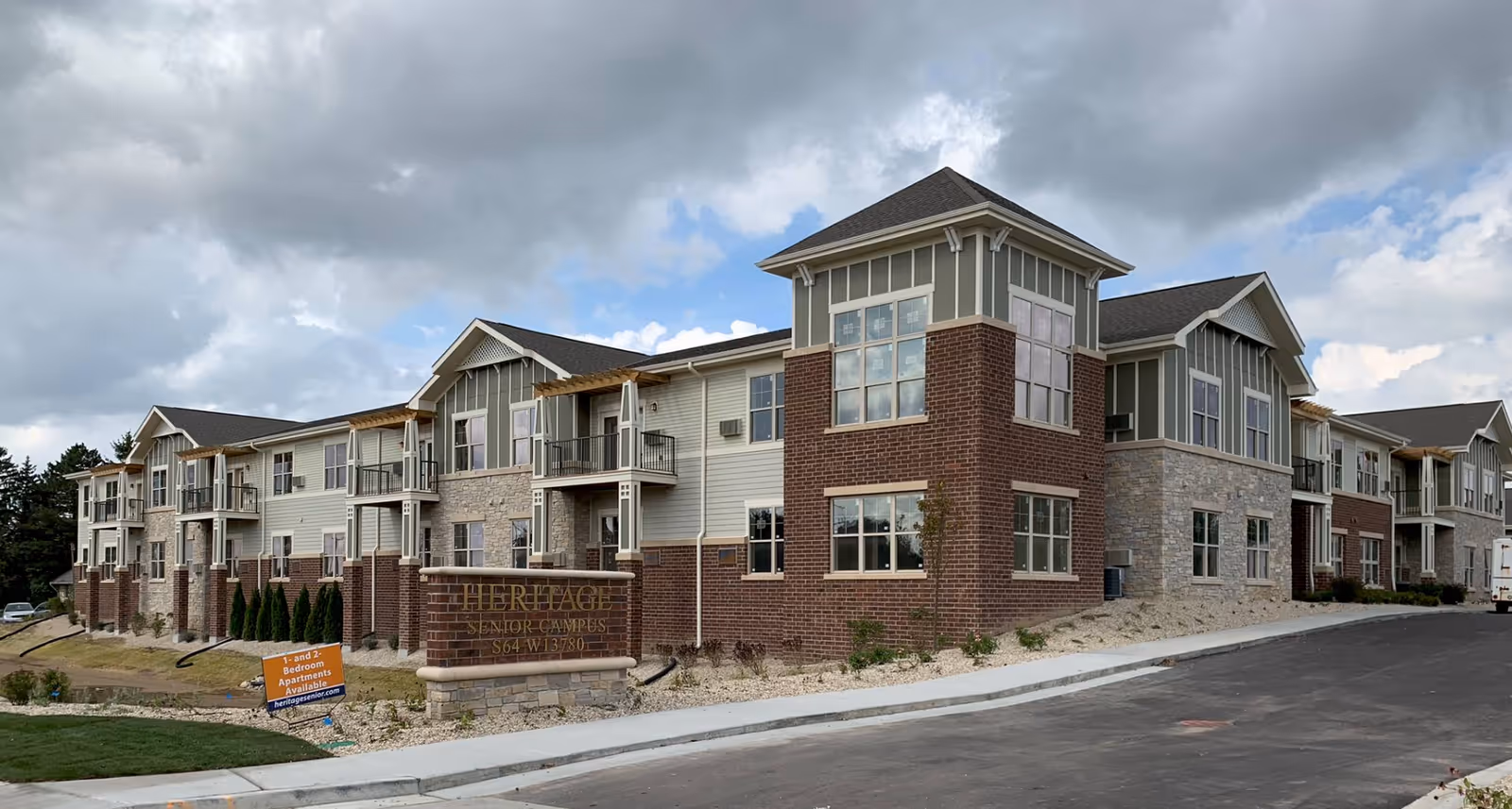 A modern two-story senior living campus with brick accents and balconies.