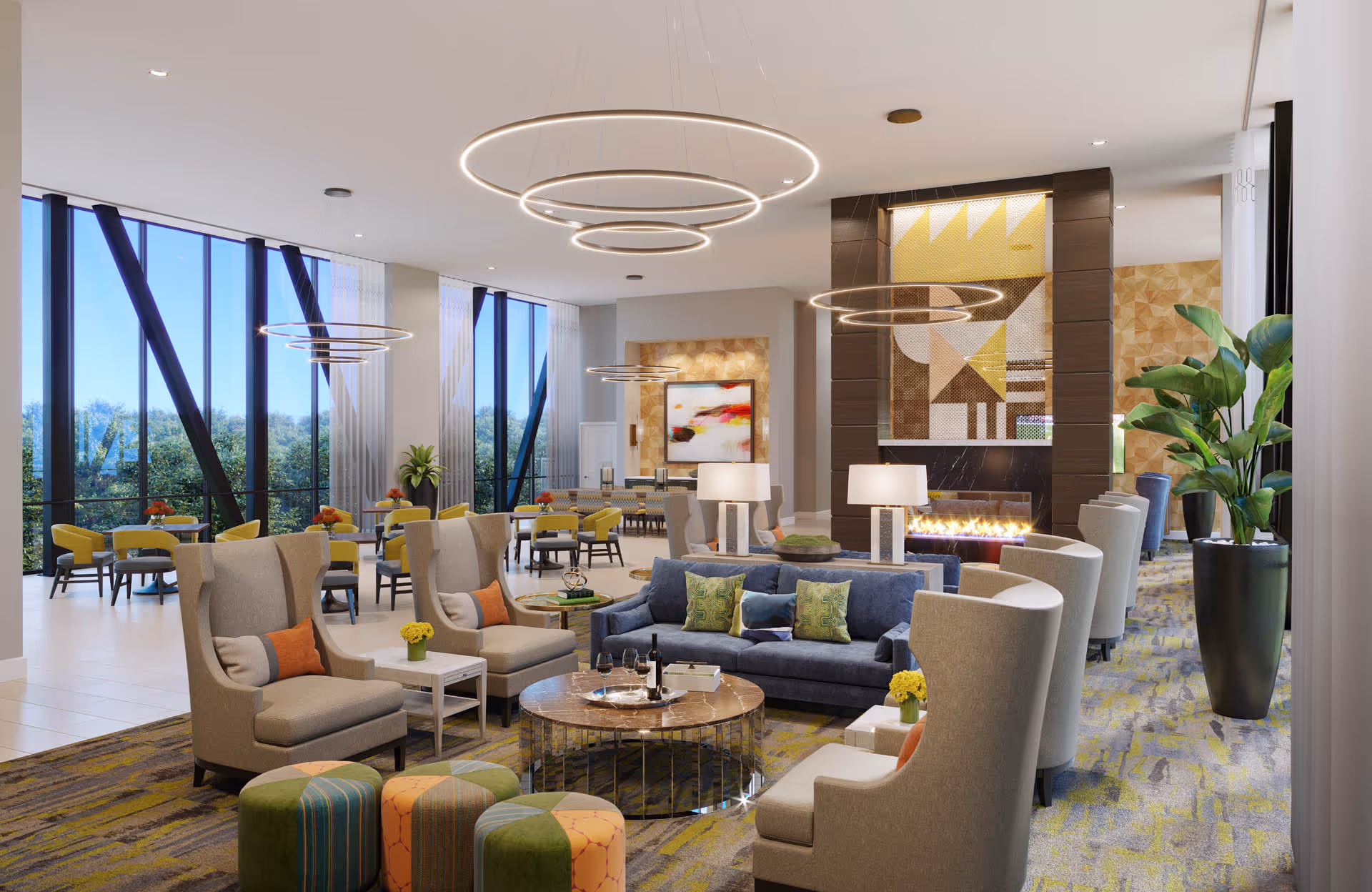 A spacious and modern living room area in a senior living facility with large floor-to-ceiling windows letting in natural light. The room features comfortable seating including armchairs, sofas with colorful cushions, round coffee tables, and ottomans. There is a contemporary fireplace with geometric artwork above it, modern circular pendant lights hanging from the ceiling, and decorative plants placed around the room.