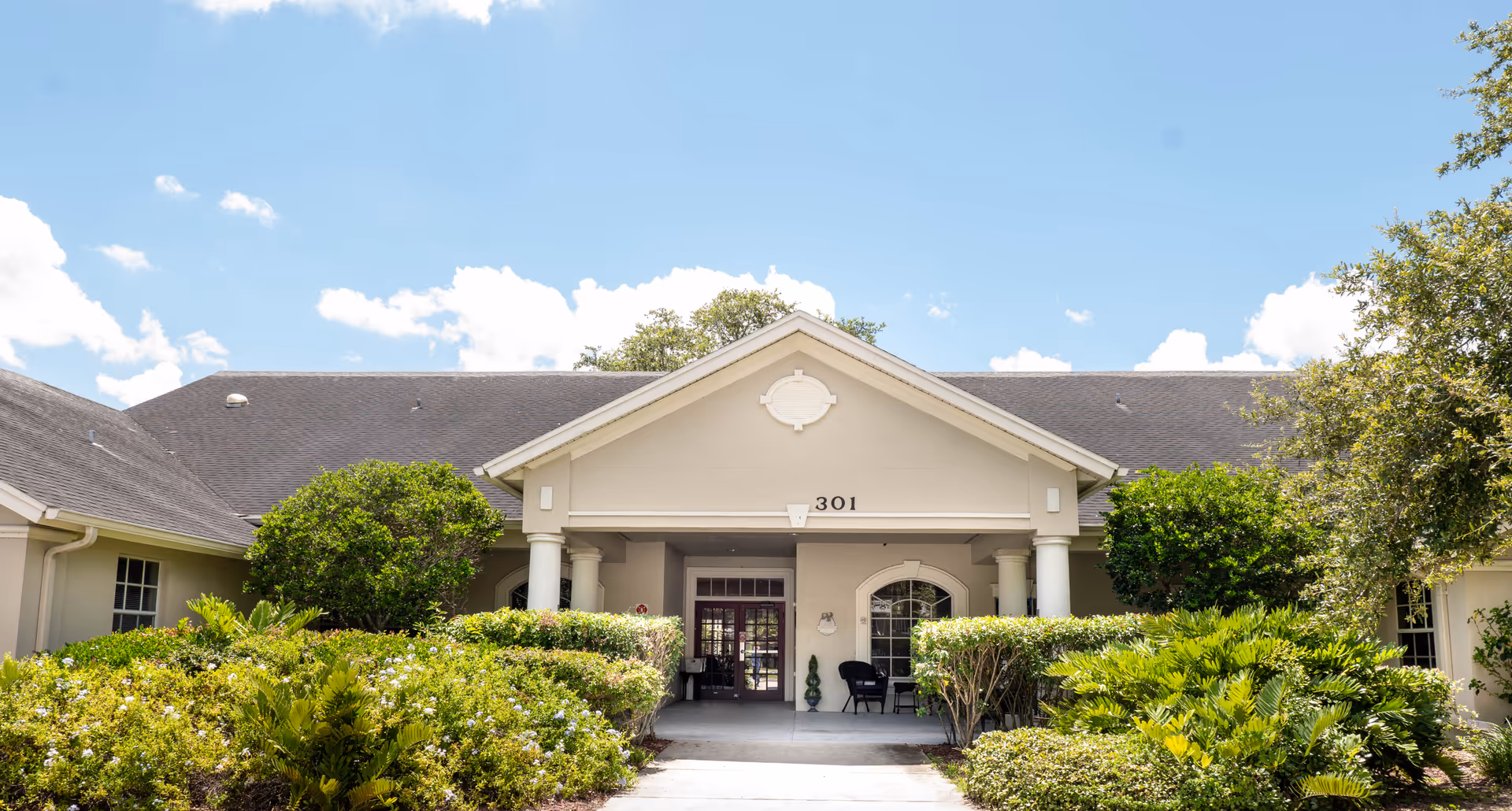 Front entrance of The Club at Haines City with columns and landscaped shrubs.