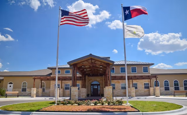 Front exterior of Stoney Brook of Copperas Cove, flags raised beside the entry canopy.