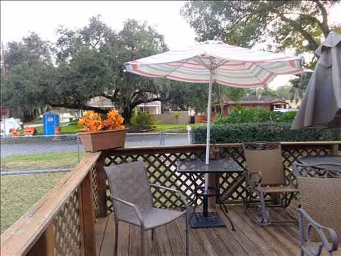 Outdoor deck seating includes an umbrella, chairs, and a table overlooking a lawn.