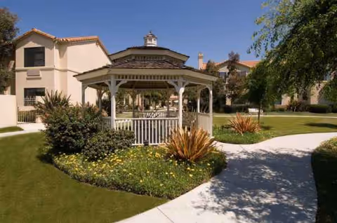 Sunny exterior view of a senior living campus with a gazebo and landscaped paths.