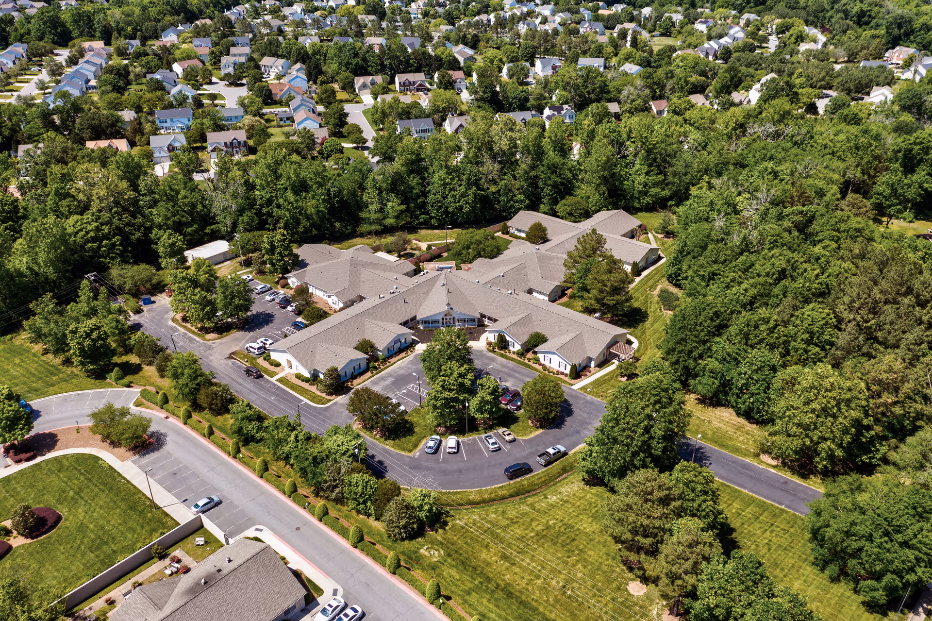 Aerial view of TerraBella Harrisburg facility surrounded by trees and greenery, with a parking lot and nearby residential neighborhood visible.