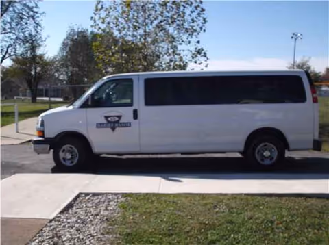 White van parked outside Maries Manor facility beside sidewalk and trees