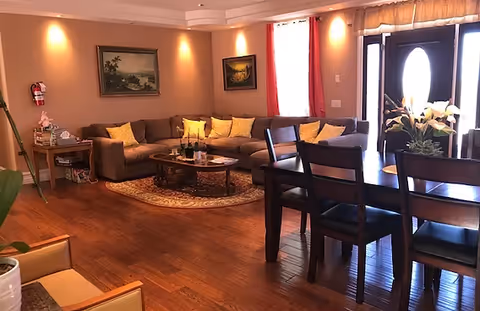 A cozy living area featuring a sectional sofa, dining table, and decorative paintings.