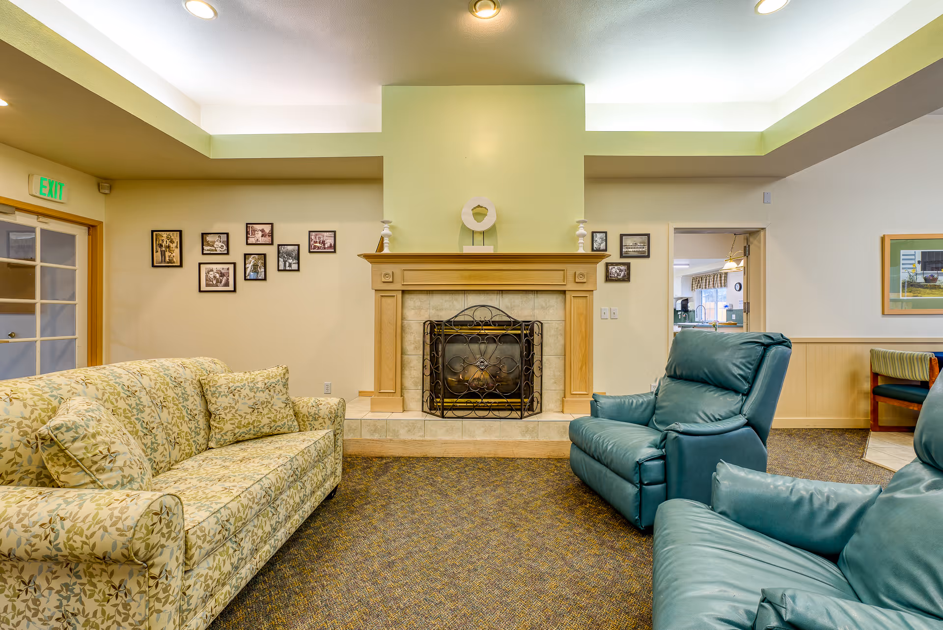 Comfortable living room with a floral sofa, teal recliners, and a central fireplace.