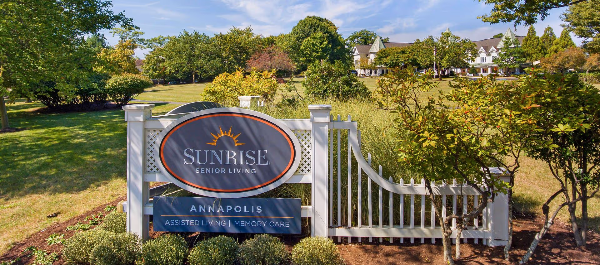 A landscaped entrance sign reading "Sunrise Senior Living Annapolis" on a lawn with the senior living building visible in the background.
