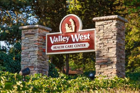 Valley West Health Care Center sign between stone pillars with greenery