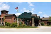 Exterior view of a Valley Hi Nursing and Rehabilitation front entrance with flagpole and blue sky.