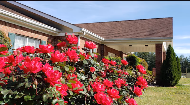 Brick facility front with pink rose bushes and a covered entrance.