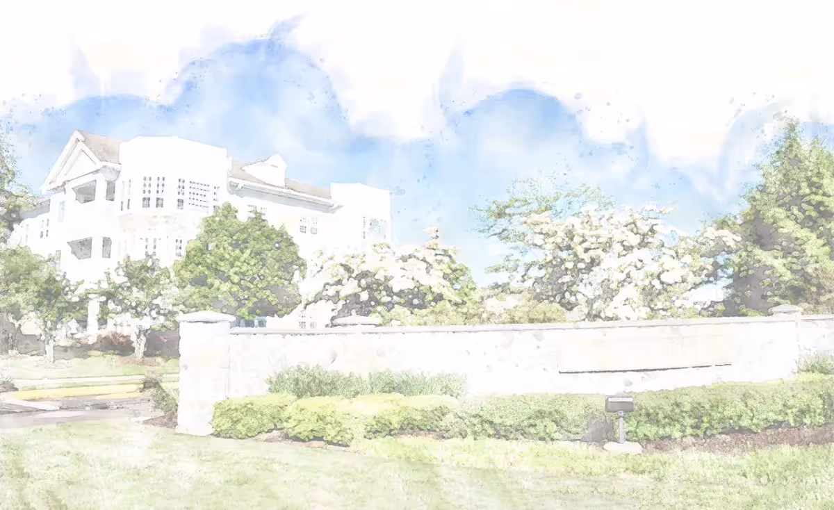 Exterior view of Avalon Health Center at StoneRidge, a white multi-story building with a stone wall and landscaped greenery.