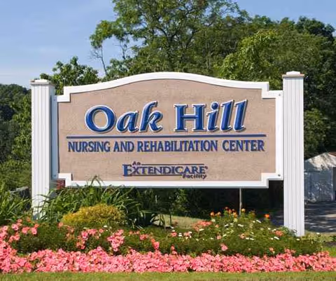 Large Oak Hill Nursing and Rehabilitation Center sign with flowering landscaping in front.