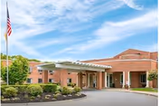 Exterior view of Life Care Center of Plymouth with brick facade, entrance canopies, flag.