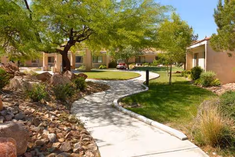 Sunlit walkway winds through a landscaped courtyard outside Life Care Center of Las Vegas.