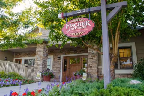 Exterior view of a senior living facility entrance with stone pillars and landscaped garden