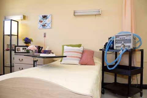 Senior living patient bedroom with bed, dresser, and medical equipment.