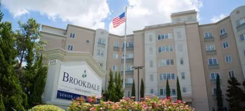 Multi-story senior living building with Brookdale sign and American flag in front.
