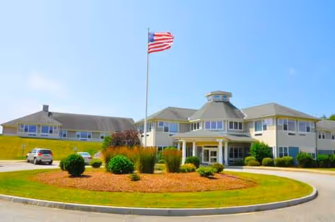 Exterior view of Sterling Village senior living facility with flagpole and circular driveway.