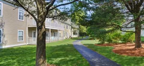 Exterior view of Brookdale Cushing Park featuring a walkway, lawn, and trees