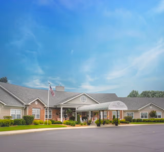 Exterior view of Franklin Manor senior living facility with awning entrance and flagpole.