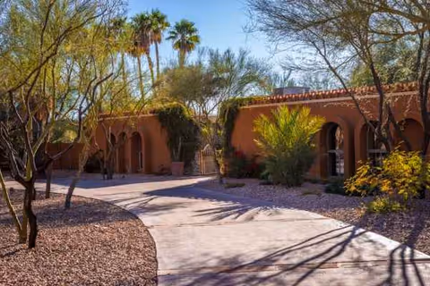 Desert-style exterior of Sunrise Care Home Shea with arches, palm trees, and a curved walkway.