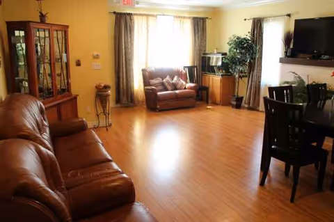 Spacious senior living room in a care home with leather sofas and plants.