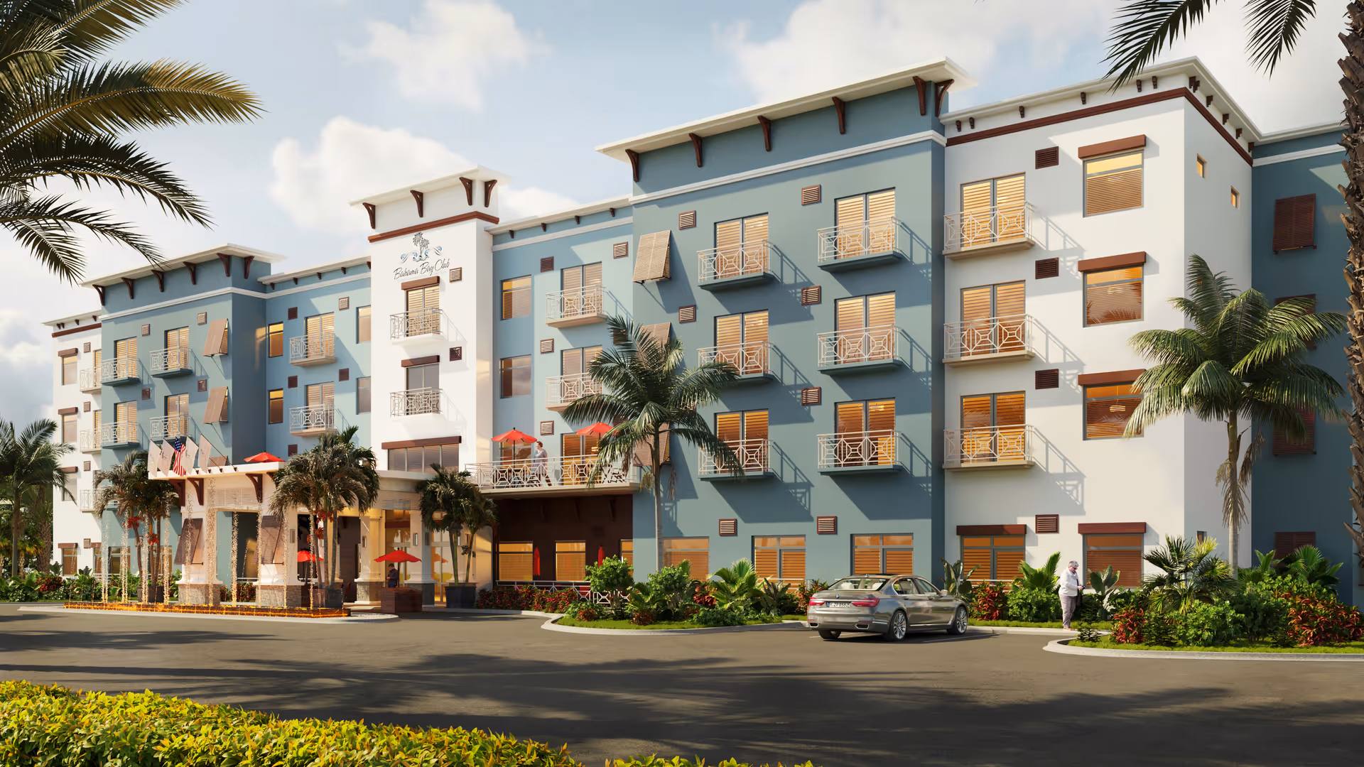 Exterior view of a modern senior living facility named Bahama Bay Club Luxury Senior Living, featuring a multi-story building with balconies, palm trees, and a driveway with a parked car and a person walking nearby under a partly cloudy sky.