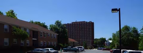 Exterior view of St. Paul Apartments with brick buildings, parked cars, and trees.