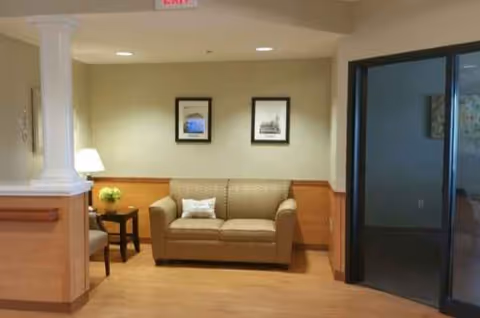 Neutral lounge area with beige sofa, side table, lamp, and glass door.