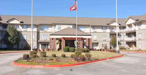 Exterior view of South Wind Heights senior living facility with circular drive and flagpoles.