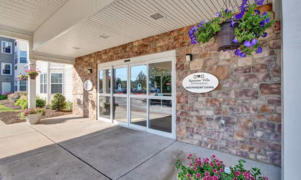 Covered front entrance with sliding glass doors, stone facade, and hanging flower baskets at Keystone Villa.