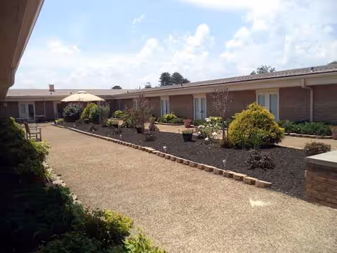 Outdoor courtyard at Sweetwater Nursing Center with planters, seating, and a central path