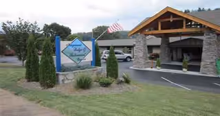 Exterior view of Haywood Lodge entrance with sign, flag, and stone pillars.