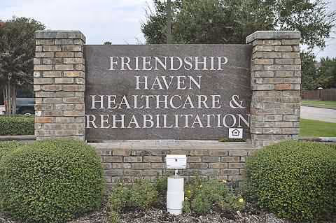 A stone entrance sign reading Friendship Haven Healthcare and Rehabilitation stands amid shrubs.