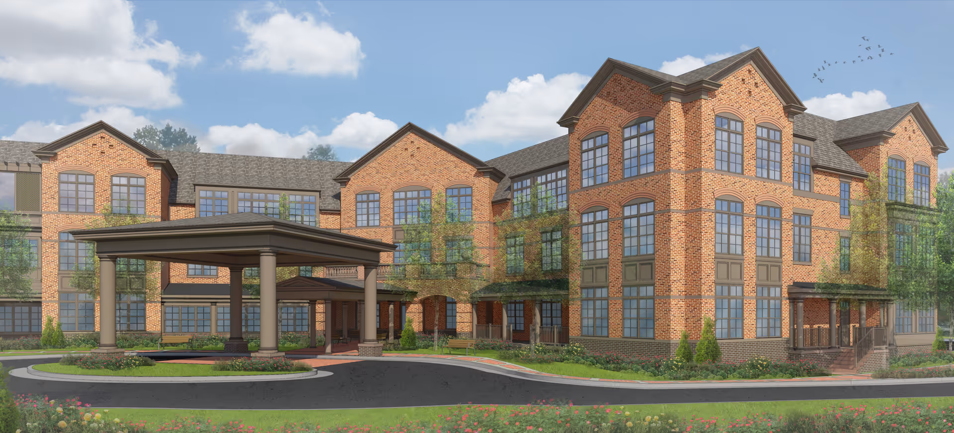 Exterior view of a large three-story brick building with many windows, a covered driveway entrance, landscaped greenery, and a partly cloudy sky with birds flying.