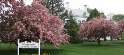 Bridgewater Nursing Home front exterior with pink flowering trees and green lawn.